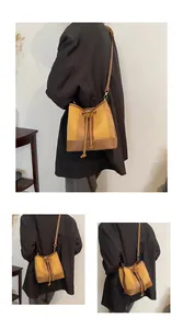 Close-up of woven color-block bucket bag with brown leather drawstring and trim