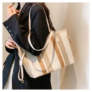 Detail van een grote gestreepte canvas shopper gedragen over de schouder op een blazer