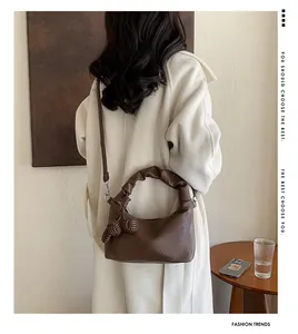 Detail of a brown lychee-textured shoulder bag with stylish knotted handle and soft leather