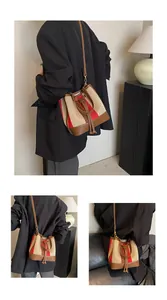 Detail view of striped bucket bag with drawstring closure and brown leather strap