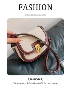 Detail of retro saddle bag with beige canvas, burgundy leather trim and gold metal buckle