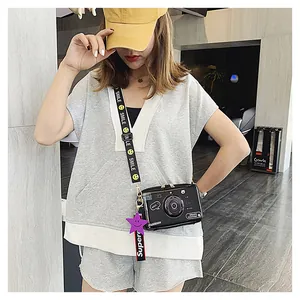 Detail of creative camera shaped crossbody bag with smile strap and star pendant