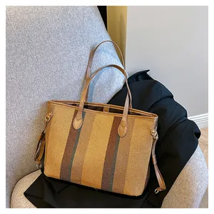 Detail van de geweven textuur en het leren handvat van een gestreepte tote bag met gesp