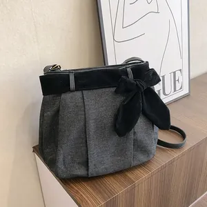 Grey denim canvas tote bag with black velvet bow decoration on wooden cabinet