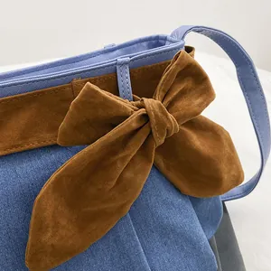 Fashionable denim canvas shoulder bag with large brown suede bow and contrast stitching