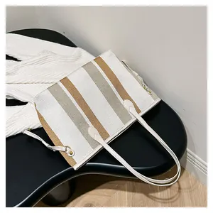 Detailweergave van gestreepte canvas shopper met geweven textuur en goudkleurige hardware