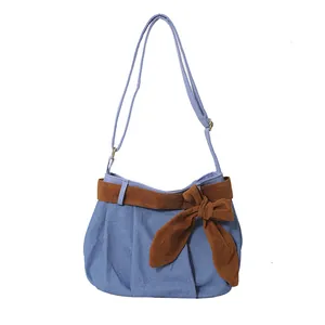 Chic light blue canvas shoulder bag with brown suede bow and adjustable strap