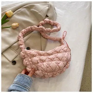 Detalle de un bolso de hombro acolchado rosa con correa fruncida y cremallera