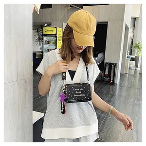 Detail showing camera-style crossbody bag with heart pattern and wide smile strap