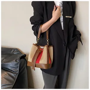 Close-up of a striped bucket bag with drawstring closure on a model in a black suit