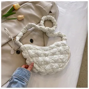 Detalle de un bolso nube blanco con textura acolchada y correa plisada elegante
