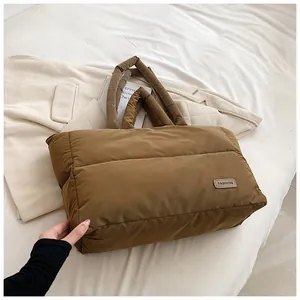 Détail d'un sac cabas matelassé marron avec étiquette mode en cuir sur un lit douillet