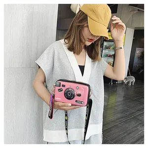 Detail of pink camera-shaped crossbody bag with a wide smile patterned strap
