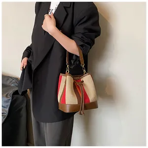 Close-up of retro striped bucket bag featuring woven texture and brown leather trim details