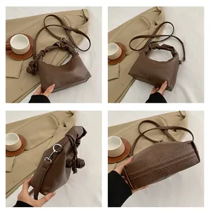 Detail view of coffee brown textured leather bag showing shoulder strap and side knot deco