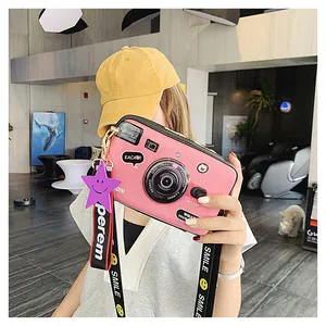 Detailed shot of pink camera-shaped crossbody bag with SMILE lettered strap and cute icons