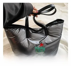Détail d'un sac cabas argenté matelassé avec broderie Merry Christmas et anses cuir