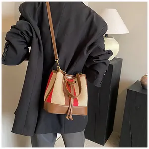 Detail of striped bucket bag with drawstring closure and brown leather trim on model