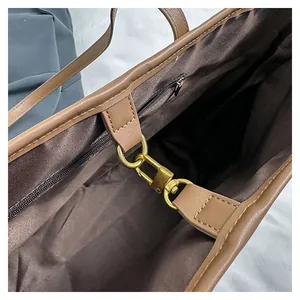 Detail van bruine shopper met gouden metalen haaksluiting en fijn stikselwerk