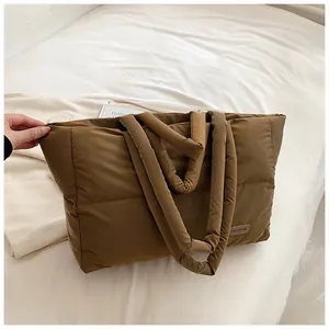 Détail du sac cabas matelassé marron foncé avec anses rembourrées et étiquette mode