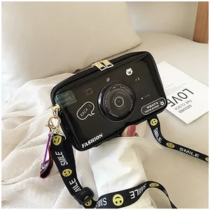 Detail of glossy black camera-shaped crossbody bag with decorative smile strap