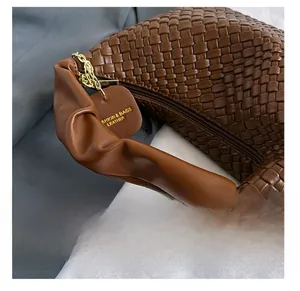 Détail d'un sac à main marron en cuir PU tressé avec chaîne dorée et anse plissée