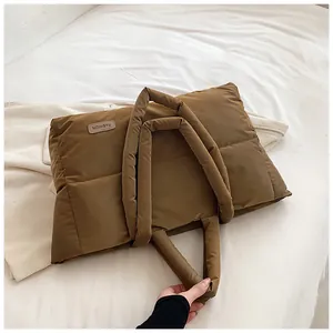 Détail d'un cabas matelassé marron avec texture en nylon brillant et étiquette mode