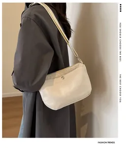 Detail view of beige canvas shoulder bag featuring front pocket and adjustable strap