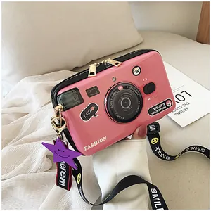 Detailed view of pink camera-shaped crossbody bag with wide SMILE printed strap