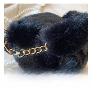 Close-up of black faux fur bag texture with chunky gold chain and pearl necklace detail