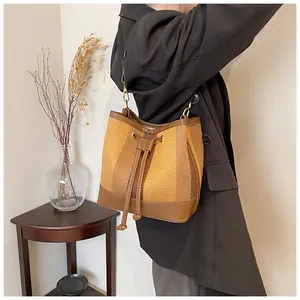 Detail of vintage striped bucket bag with brown leather trim and golden hardware