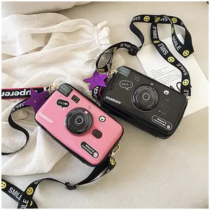 Detail of creative camera-shaped crossbody bags in pink and black with wide smile straps