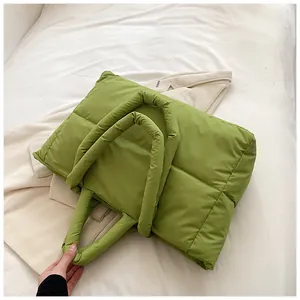 Gros plan du sac cabas matelassé vert posé sur un tricot blanc de qualité