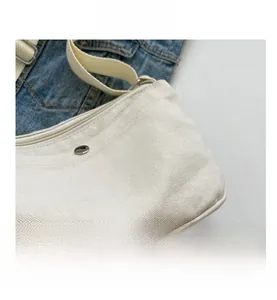 Detail of cream canvas bag fabric with metal magnetic snap and adjustable strap