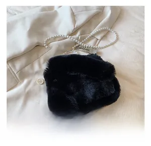 Detail showing the plush black faux fur texture and elegant pearl chain with metal logo