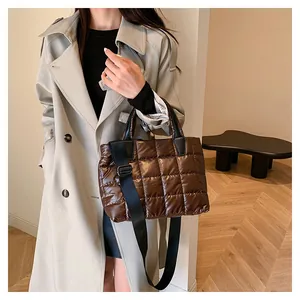 Dettaglio di una borsa imbottita trapuntata con motivo a quadri e tracolla larga nera
