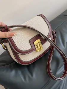 Vintage canvas and burgundy leather saddle bag with gold buckle on black leather sofa