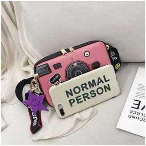 Detail of pink vintage camera-shaped crossbody bag with dual zippers and decorative charms
