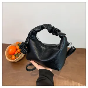 Detail of black leather crescent bag with scrunched handle and decorative knot detail