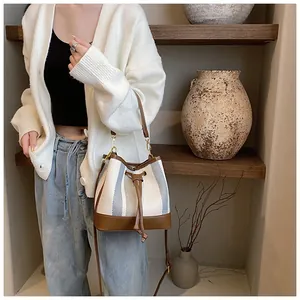 Detail of striped woven bucket bag featuring brown leather trim and drawstring closure