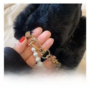 Detailed close-up of plush black faux fur bag with gold hardware and pearl chain strap