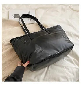 Détail du sac cabas matelassé noir brillant sur un fond en polaire blanche douce