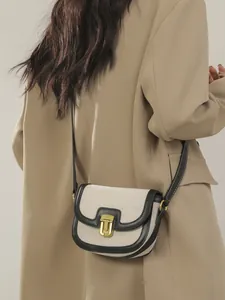 Retro canvas saddle bag with black leather trim and gold buckle shown on shoulder