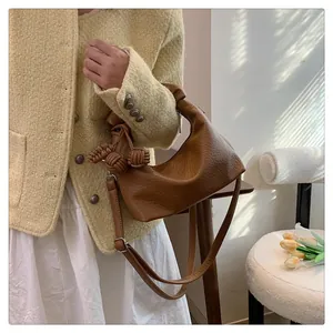 Detail of vintage brown leather crescent bag with unique knot detail and woven charms