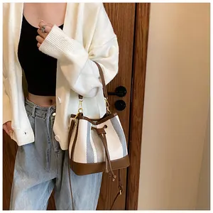 Detail of drawstring bucket bag with striped canvas and brown leather accents