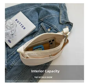 Detail view of the interior capacity of a cream canvas crossbody bag with compartments