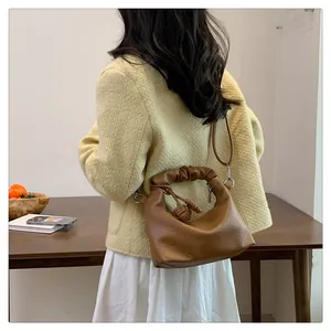 Detail of a brown lychee pattern leather shoulder bag with pleated handle and silver hardware