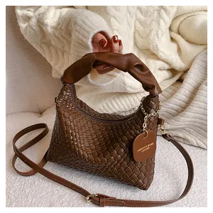 Détail du sac à main tissé marron avec poignée froncée et décorations dorées