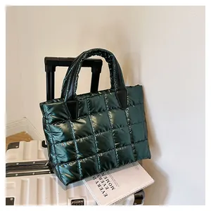 Dettaglio della borsa imbottita verde scuro metallizzata su una valigia d'argento