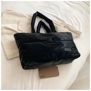 Gros plan d'un sac cabas noir matelassé avec étiquette de mode et téléphone pour échelle